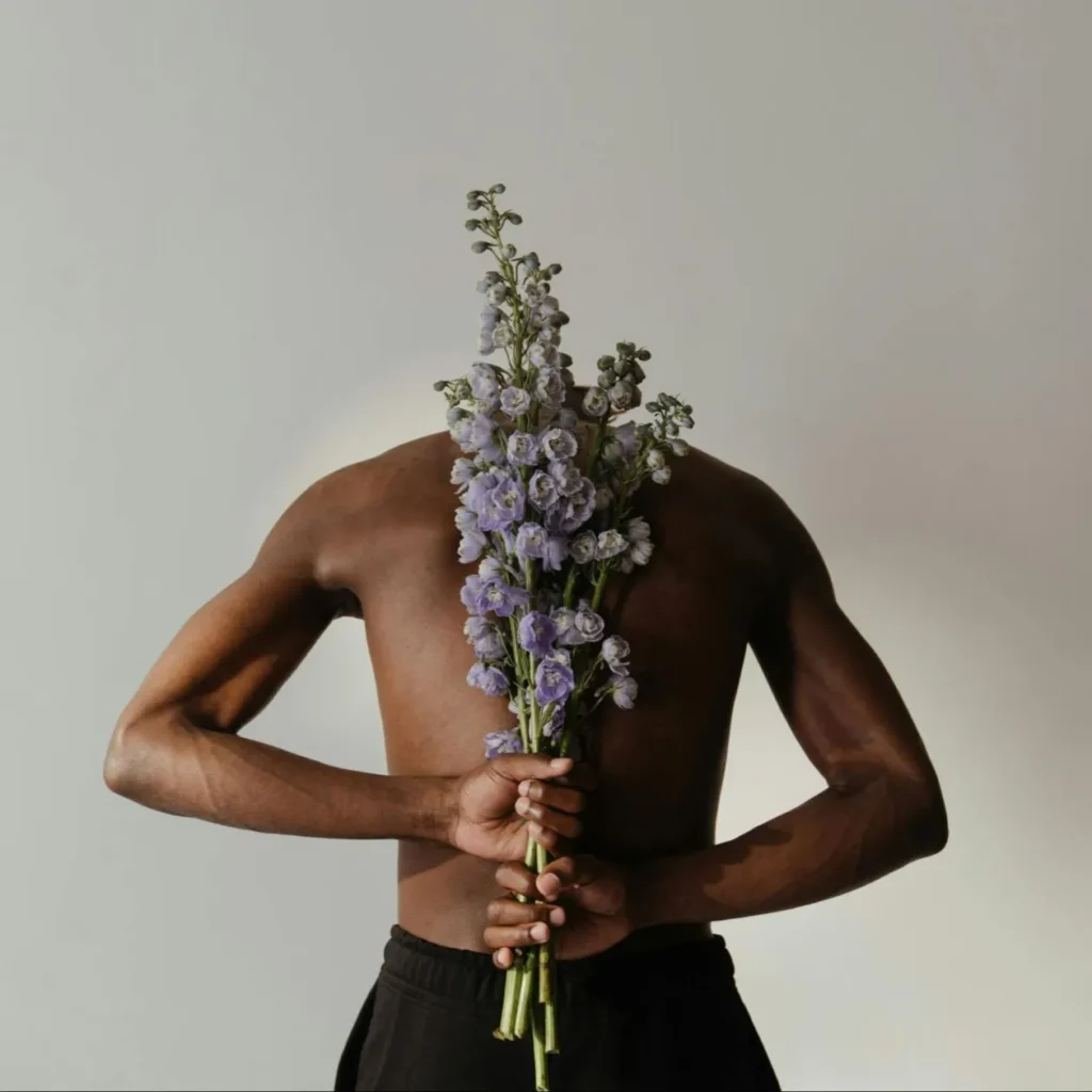Abstract of man's back holding purple flowers